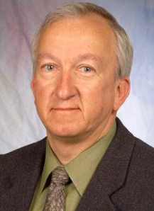 Headshot of Prof. Bob Karlicek: a white man with grey hair wearing a green shirt and tie with a black blazer on a grey background