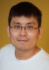 headshot of east Asian man with black hair and glasses wearing a white shirt on a yellow background