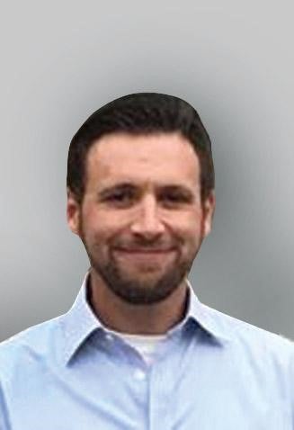 headshot of white man with brown hair and beard in a light blue collared shirt on a grey background